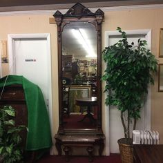 a mirror sitting next to a potted plant on top of a wooden table in front of a doorway