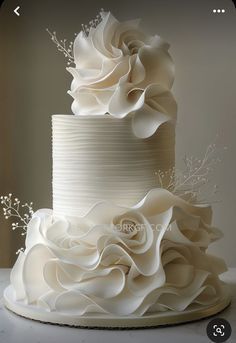 a three tiered white wedding cake with flowers on top