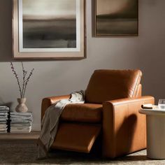 a brown recliner chair sitting in a living room next to a table with a vase on it