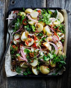 a tray filled with lots of food sitting on top of a wooden table next to a fork