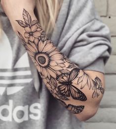 a woman's arm with sunflowers and butterflies tattooed on the arm,