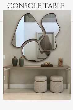 a console table with two stools and a mirror on the wall in front of it