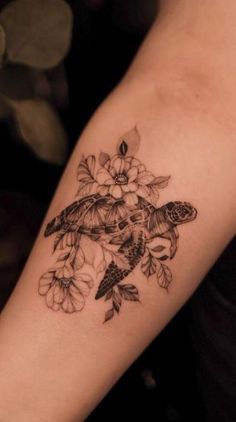 a woman's arm with a turtle and flowers tattoo on it