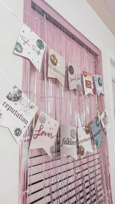 there are many different types of cards on the wall hanging from a pink door frame