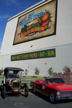 two cars parked in front of a building with a sign on it's side