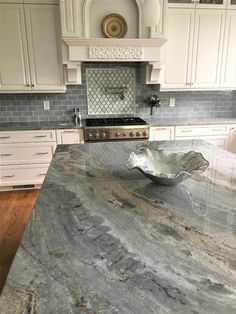 a large kitchen with marble counter tops and white cabinets in the center, along with an oven