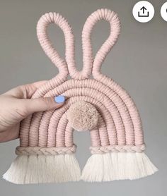 a person holding up a pink bunny hat with tassels