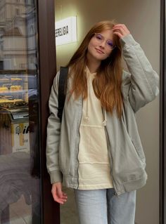 a woman standing in front of a glass door with her hand on her head and looking at the camera