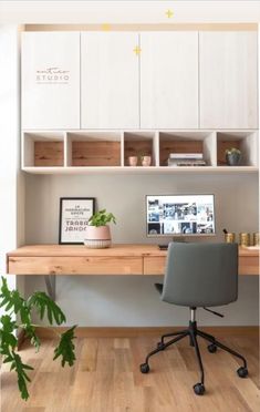 a desk with a computer and some plants on top of it in front of a white cabinet