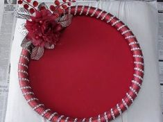 a red cake with silver trim and flowers on top