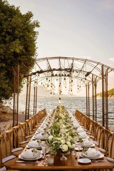 a long table set up with white flowers and greenery for an outdoor wedding reception