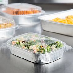 plastic containers filled with food sitting on top of a metal counter next to other trays