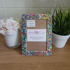 a photo frame sitting on top of a wooden table next to a potted plant