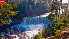 a large waterfall in the middle of a forest with blue water coming out of it