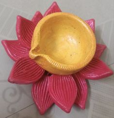 a yellow bowl sitting on top of a pink flower shaped object in the shape of a lotus