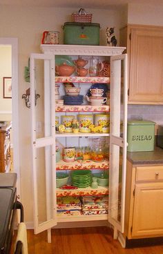 an open refrigerator in a kitchen with lots of dishes on the shelves and plates inside