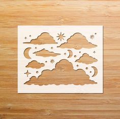 a cutout of clouds and stars on a wooden surface