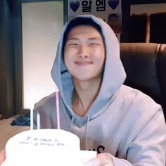 a young man sitting in front of a cake