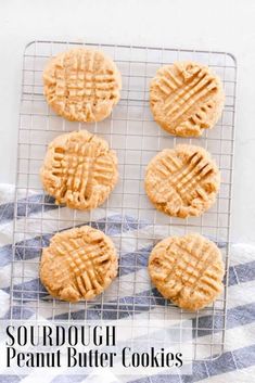 four peanut butter cookies on a cooling rack with the words, sourdough peanut butter cookies