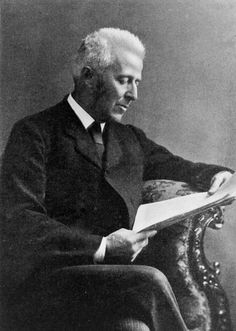 an old black and white photo of a man sitting in a chair holding a book