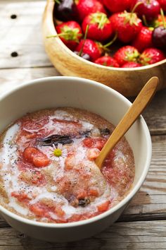 a bowl of food with strawberries in it and a wooden spoon next to the bowl