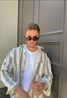 a man wearing sunglasses standing in front of a door