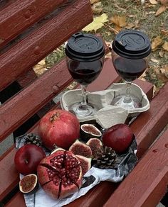 a wooden bench topped with lots of fruit next to two wine glasses on top of it