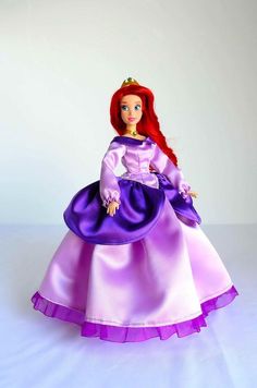 the doll is wearing a purple dress and tiara