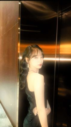 a woman standing in an elevator with her back turned to the camera and wearing a black dress