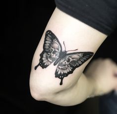 a black and white butterfly tattoo on the left foot, with a skull in the middle