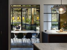 a dining room table and chairs in front of large windows