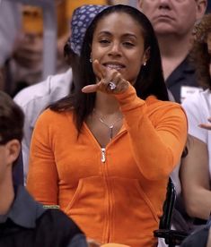 a woman in an orange shirt is holding her finger up