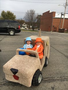 two children are riding in a fake car