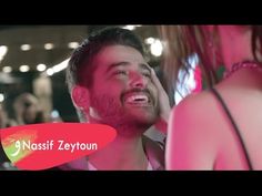 a man laughing while standing next to a woman in front of him with the words nassif zeyroun on it