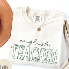 Celebrate your passion for teaching with our Comfort Colors® English Teacher Shirt. Featuring a beautiful floral design, this comfortable and stylish tee is perfect for any English teacher. It makes a thoughtful gift for educators and is a great addition to any English teacher's wardrobe. Perfect for the classroom or casual outings, this shirt showcases your love for teaching. #EnglishTeacher #TeacherShirt #EnglishTeacherGift #FloralTeacherShirt #ComfortColors #TeacherApparel #ClassroomStyle #Te Cotton T-shirt With Name Print For Teaching, White Cotton T-shirt For Teaching, White Cotton T-shirt, English Teacher Shirts, English Teacher Shirt, Teacher Aesthetic, Classroom Style, English Teacher Gifts, Teacher Wardrobe