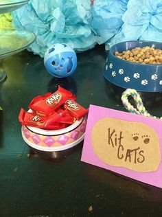 a table topped with bowls filled with candy and candies next to a sign that says kit cats