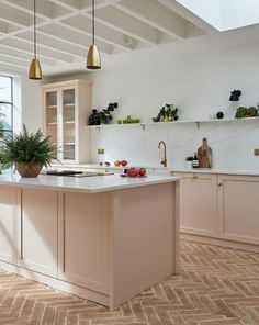 a large kitchen with an island in the middle and gold pendant lights hanging from the ceiling