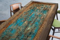 a wooden table with chairs around it and an artistic design painted on the top surface