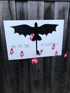 a sign that has been taped to the side of a wooden fence with red flowers on it