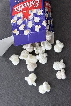 a box of popcorn sitting on top of a gray floor next to some white marshmallows