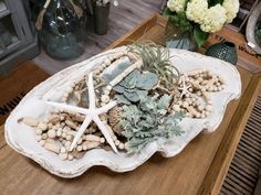 an arrangement of succulents and shells on a tray