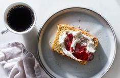 a piece of toast with whipped cream and jelly on it next to a cup of coffee