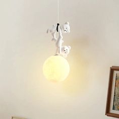 there is a lamp that has two teddy bears on top of it and one bear hanging from the ceiling