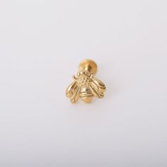 a small gold bee brooch on a white background with clippings to the side