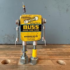 a yellow and black toy robot sitting on top of a wooden table next to screws