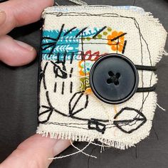 someone is holding a button on top of a piece of fabric that has been stitched together