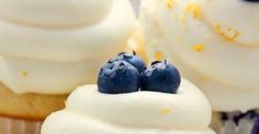 two cupcakes with white frosting and blueberries on top are sitting next to each other