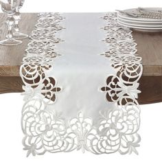 a white table runner on top of a wooden table next to wine glasses and plates