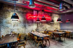 an empty restaurant with tables and chairs in front of the neon sign on the wall