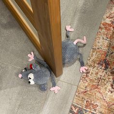 a stuffed animal laying on the floor next to a wooden door with pink legs and feet